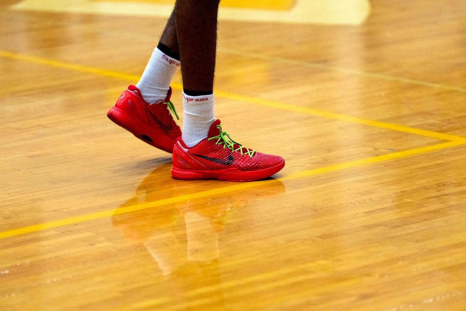 Close-up of red Nike basketball shoes on a polished hardwood court during a basketball game.
