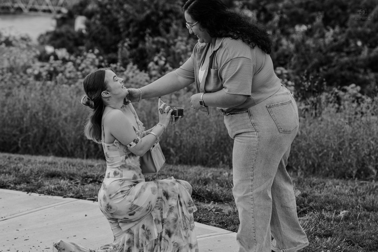 Emotional same-sex marriage proposal captured in black and white outdoor photo.