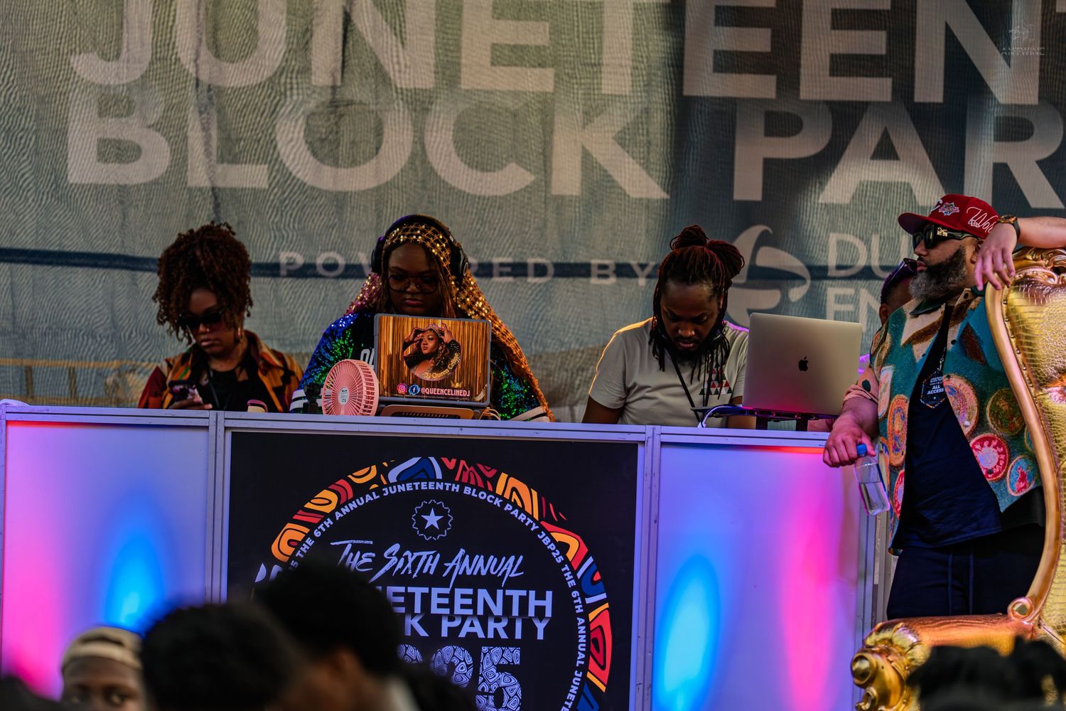DJs performing on a colorfully lit stage at the 6th Annual Juneteenth Block Party event.