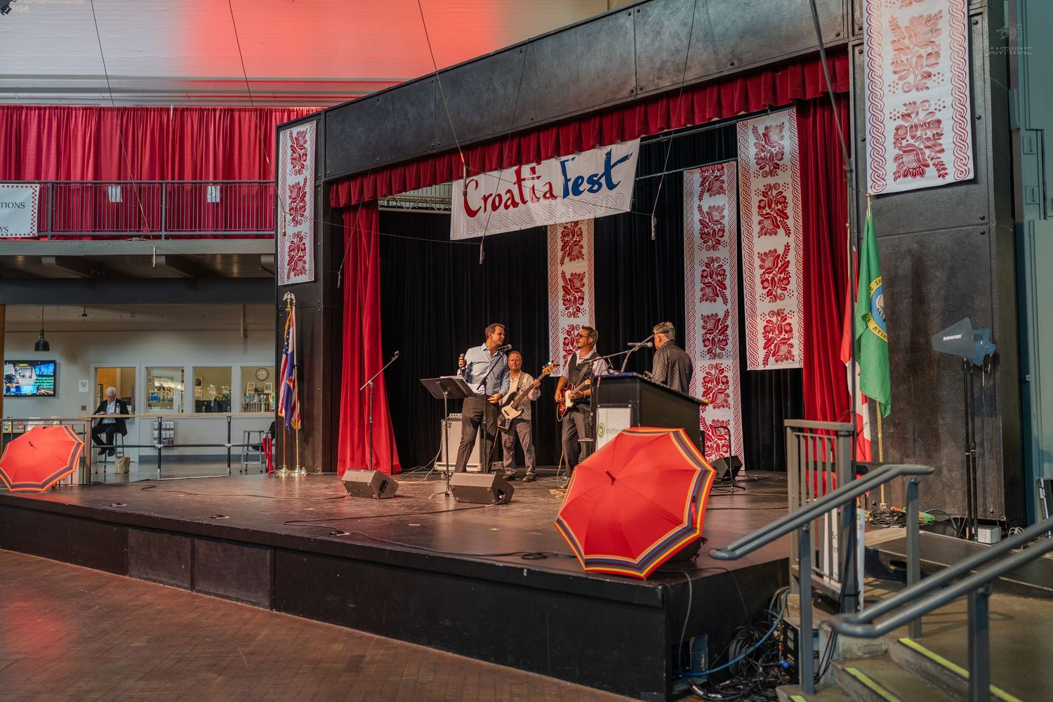 Band performs on stage at a Chinatown Fest event with red curtains and decorative banners.