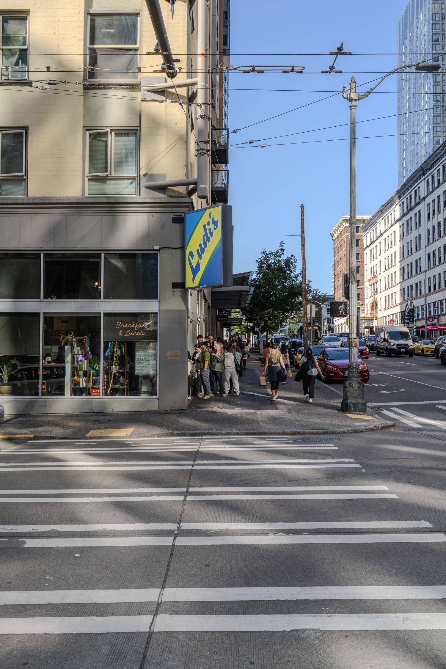 Busy urban street corner with pedestrians crossing near a Lottie's shop in Seattle.