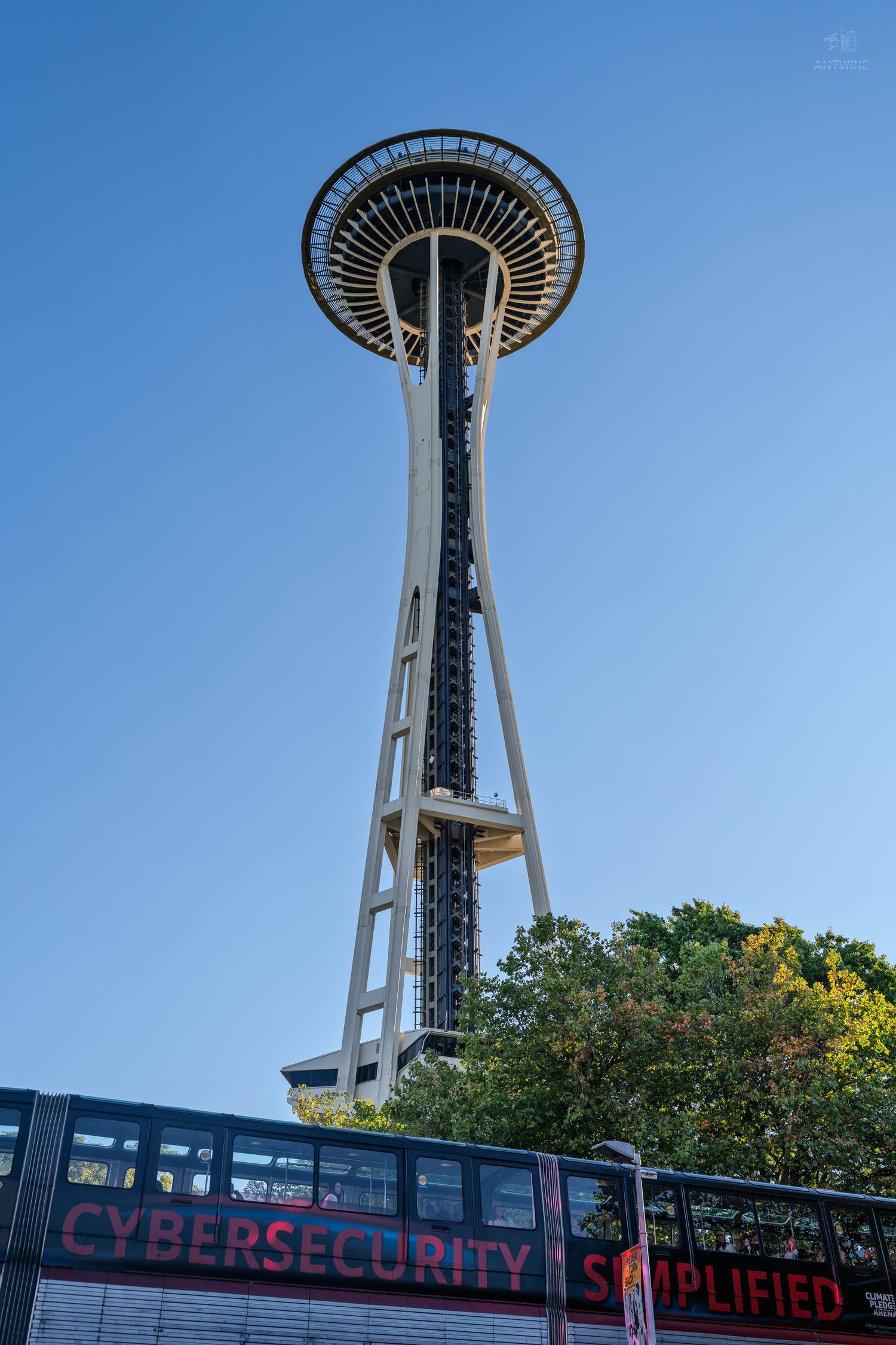 Seattle Space Needle tower against clear blue sky with Cybersecurity Simplified bus below.