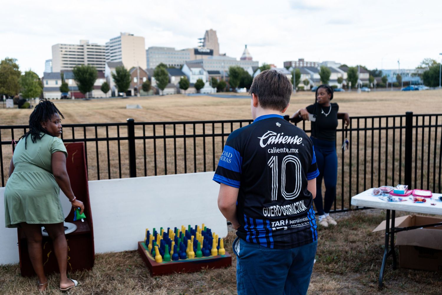 Person in Chivas jersey browsing items at an outdoor table during a community event.