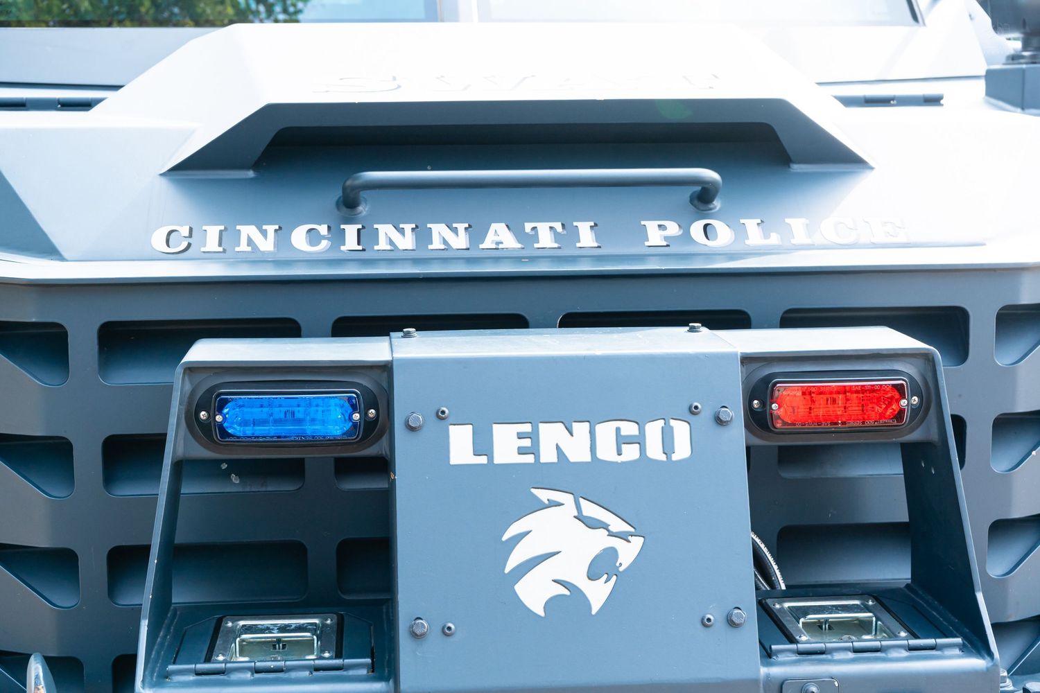 Close-up of a Lenco armored vehicle bearing Cincinnati Police markings, featuring blue and red emergency lights.