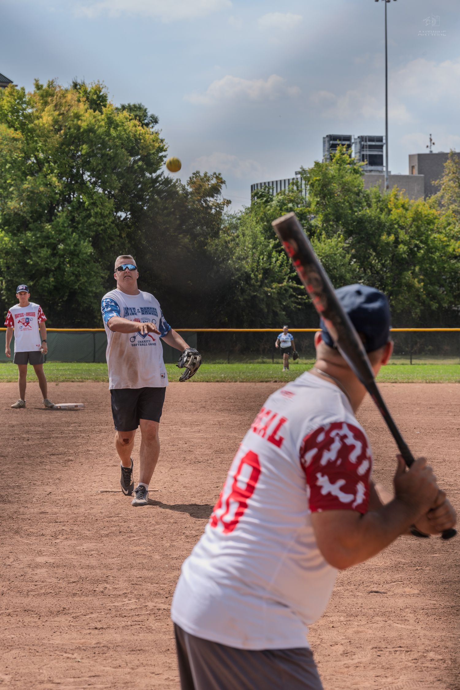 A softball pitcher throws to a batter during an outdoor charity Battle of Badges softball game.