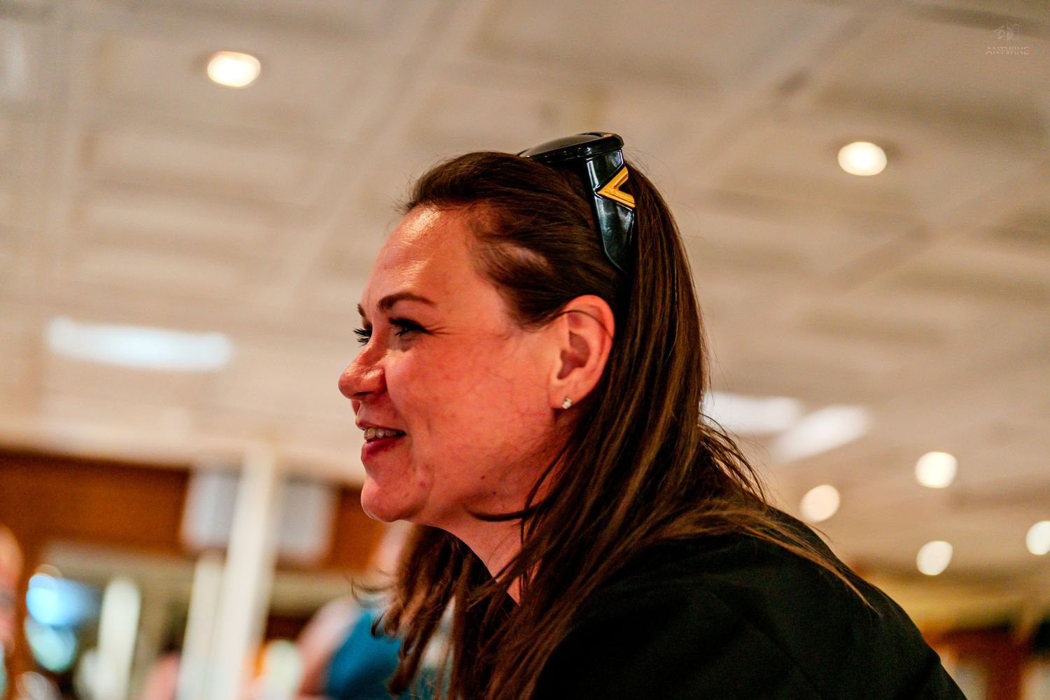 Woman with dark hair and yellow hair clip smiling at an indoor event.