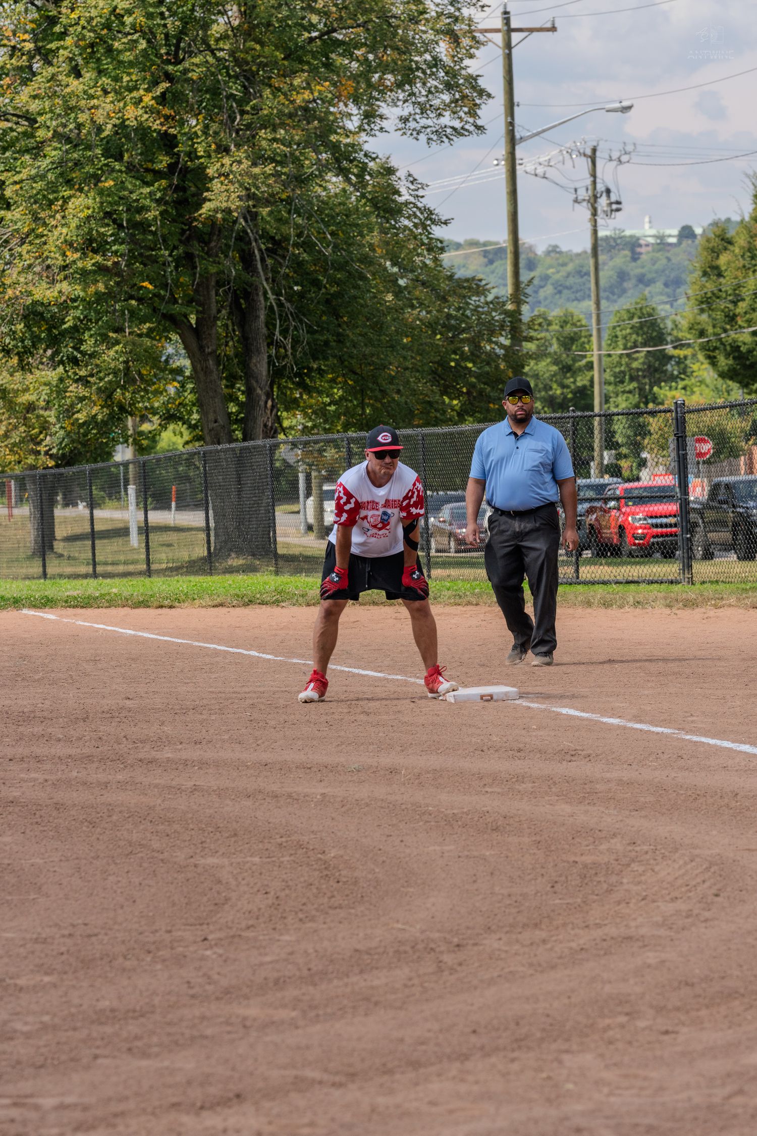 Softball player standing on base with umpire watching during an outdoor charity softball game.