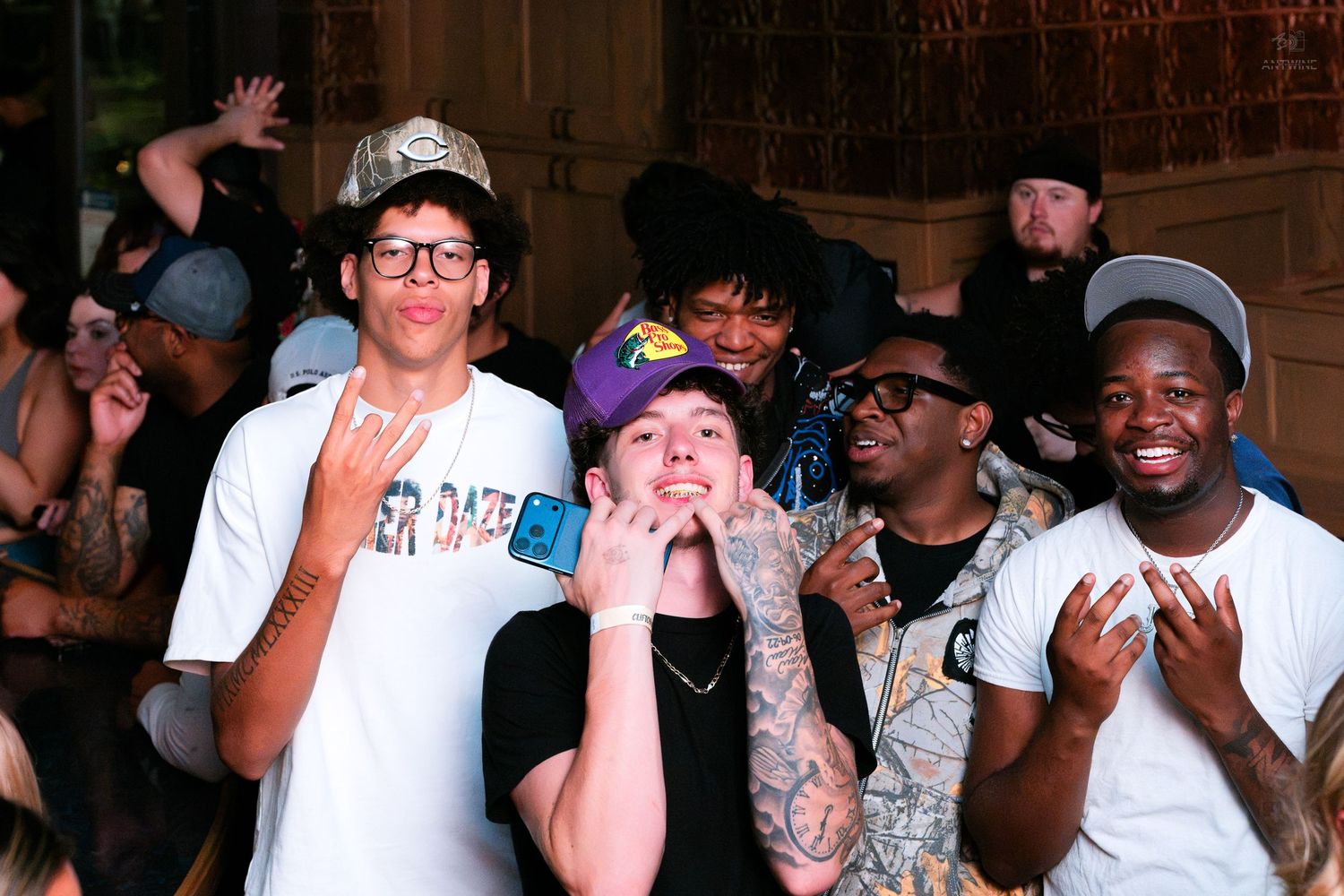 Group of young men posing and smiling at a lively outdoor party event.
