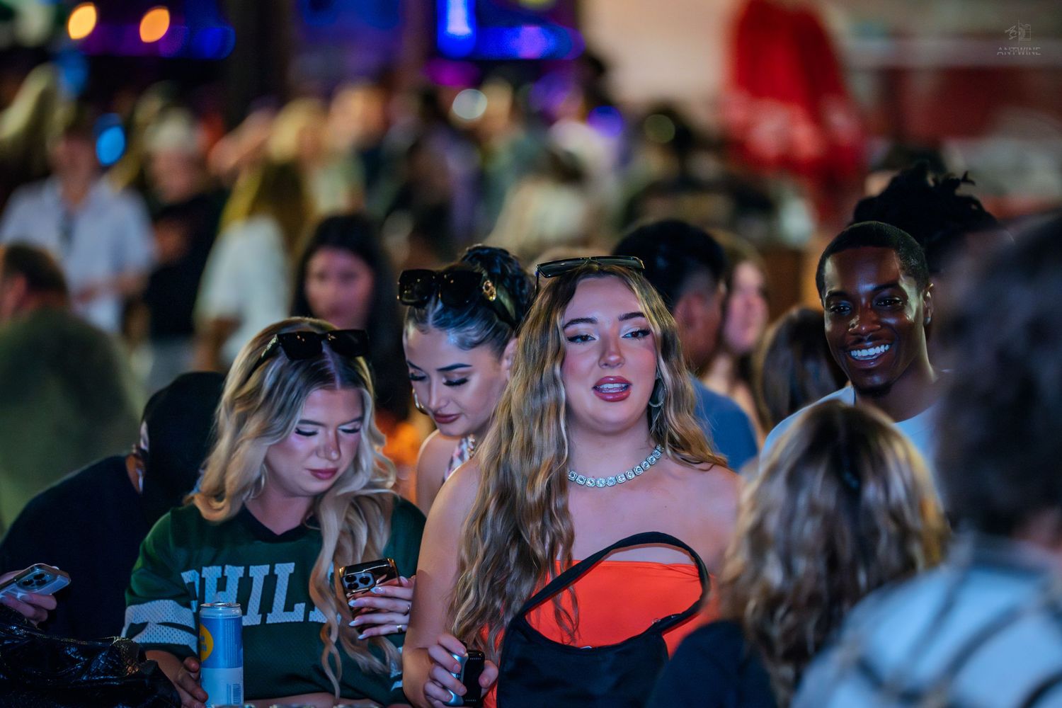 Group of young women smiling and socializing at a crowded nightclub.