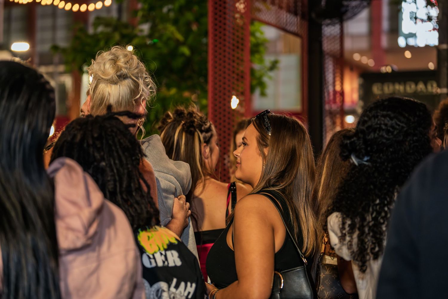 Group of women socializing together at an outdoor nighttime street event.
