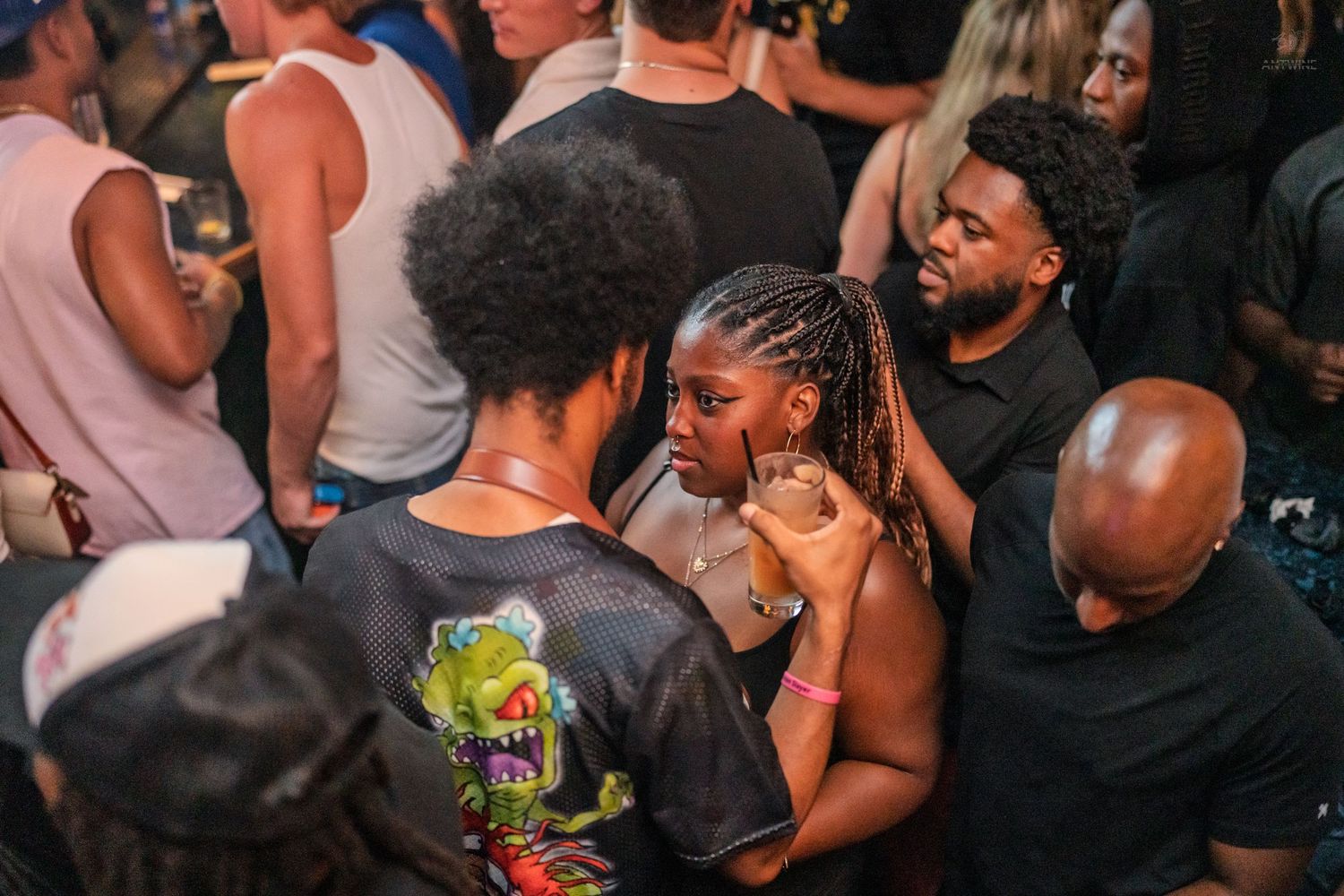 Group of friends dancing and socializing closely together at a packed indoor nightclub event.