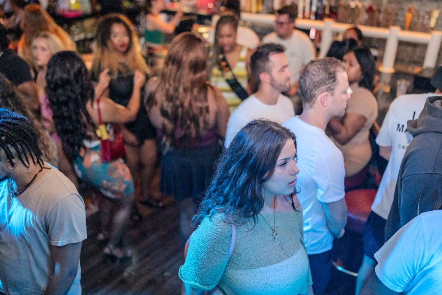 Diverse group of partygoers socializing and dancing inside a vibrant nightclub venue.
