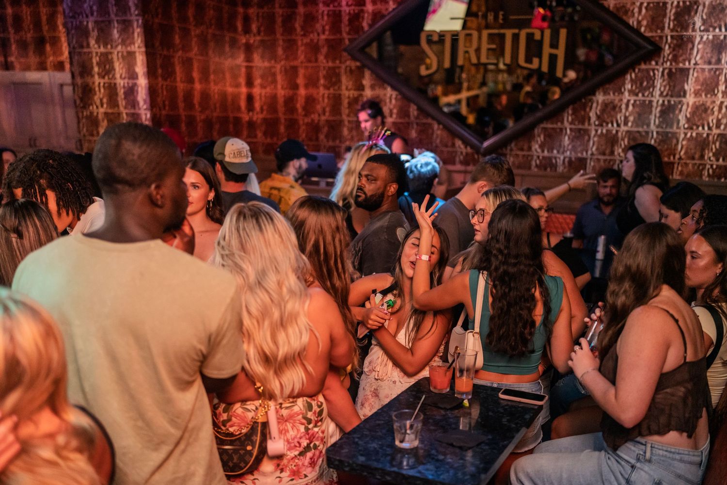Energetic crowd socializing and dancing at Stretch Bar with warm ambient lighting.