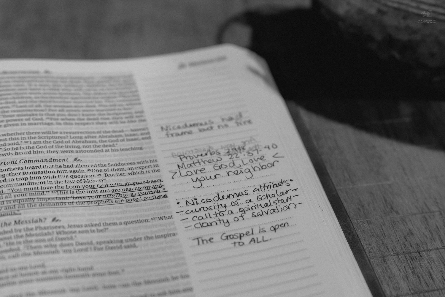 Open Bible with handwritten notes in margins on a wooden table, showing scripture study and personal reflections.