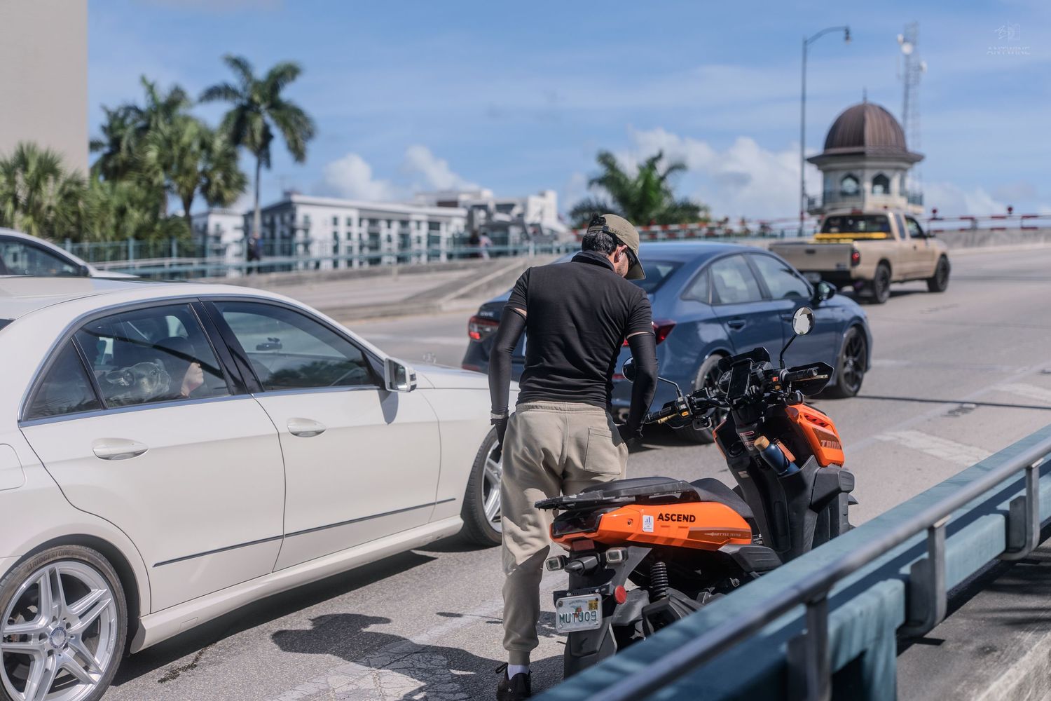 Law enforcement officer inspecting vehicles near a motorcycle on a sunny Florida coastal road.