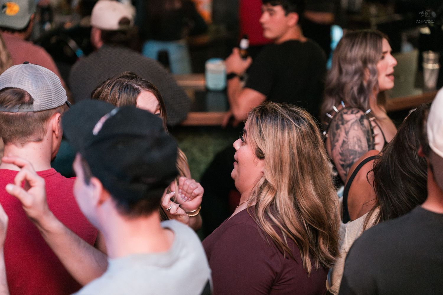 Group of people socializing and enjoying drinks at a busy indoor bar nightlife gathering.