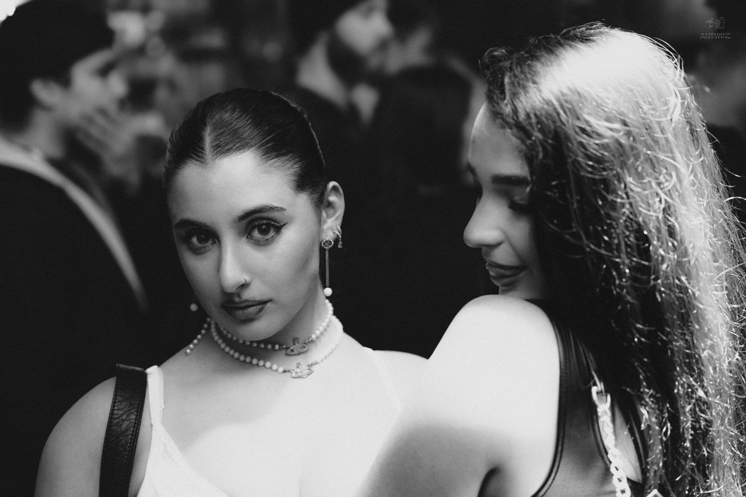Black and white photo of two elegant women at a crowded social event.