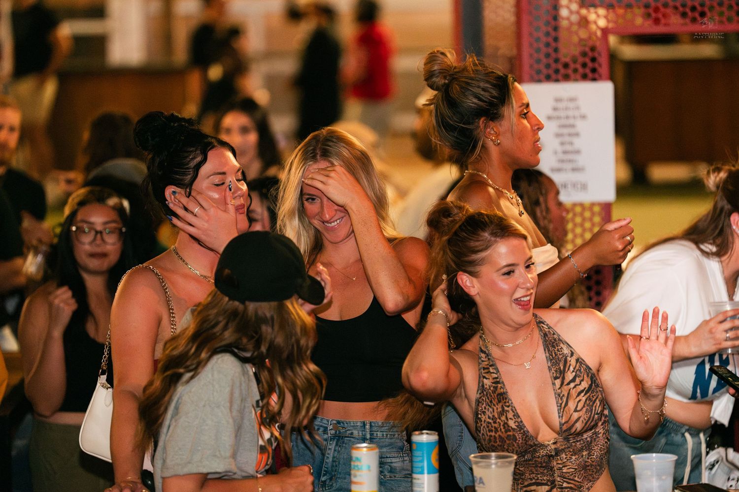 Group of young women laughing and having fun together at an outdoor nightlife event.