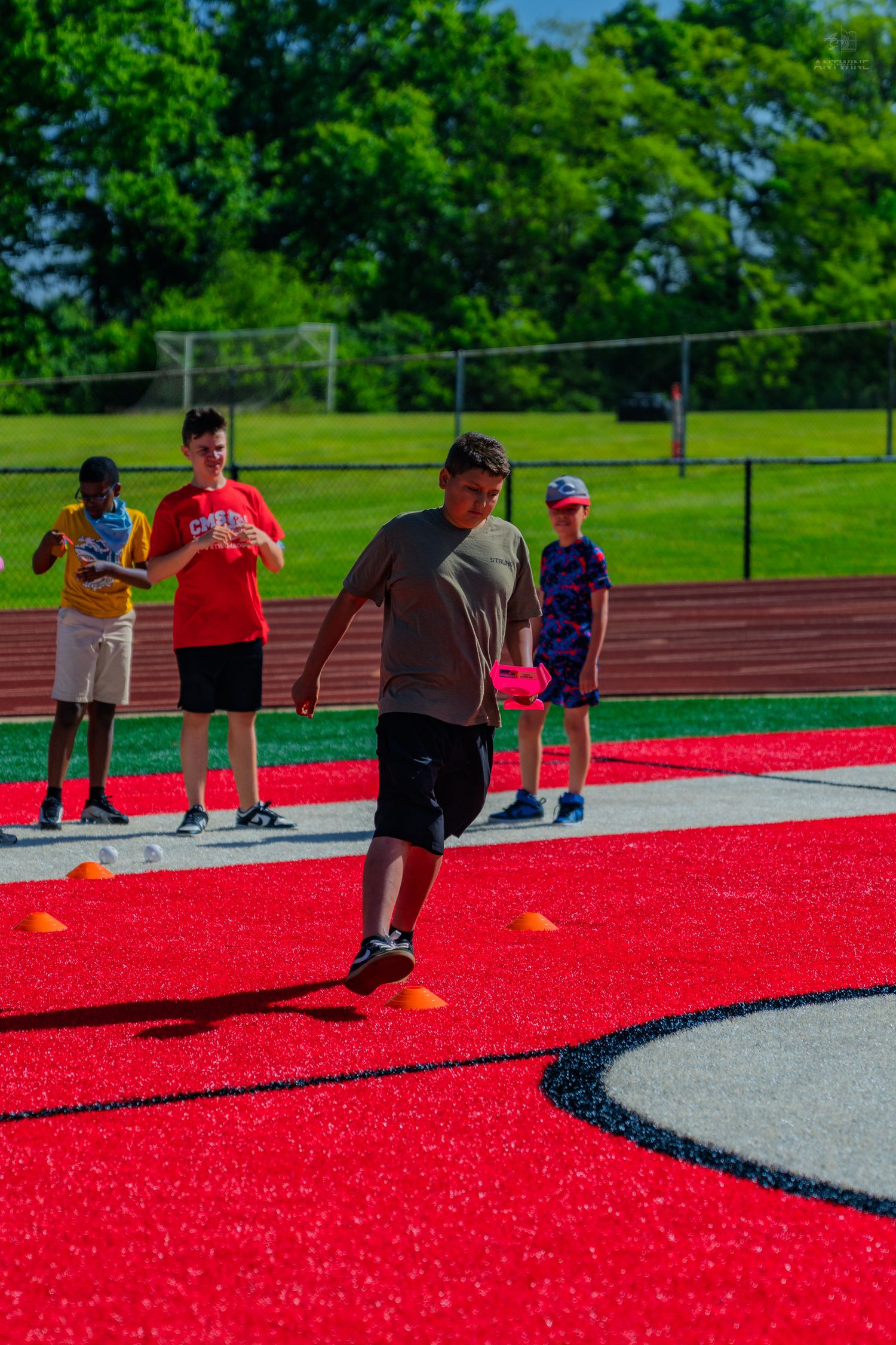 Kids participating in outdoor sports activity on red turf track field.
