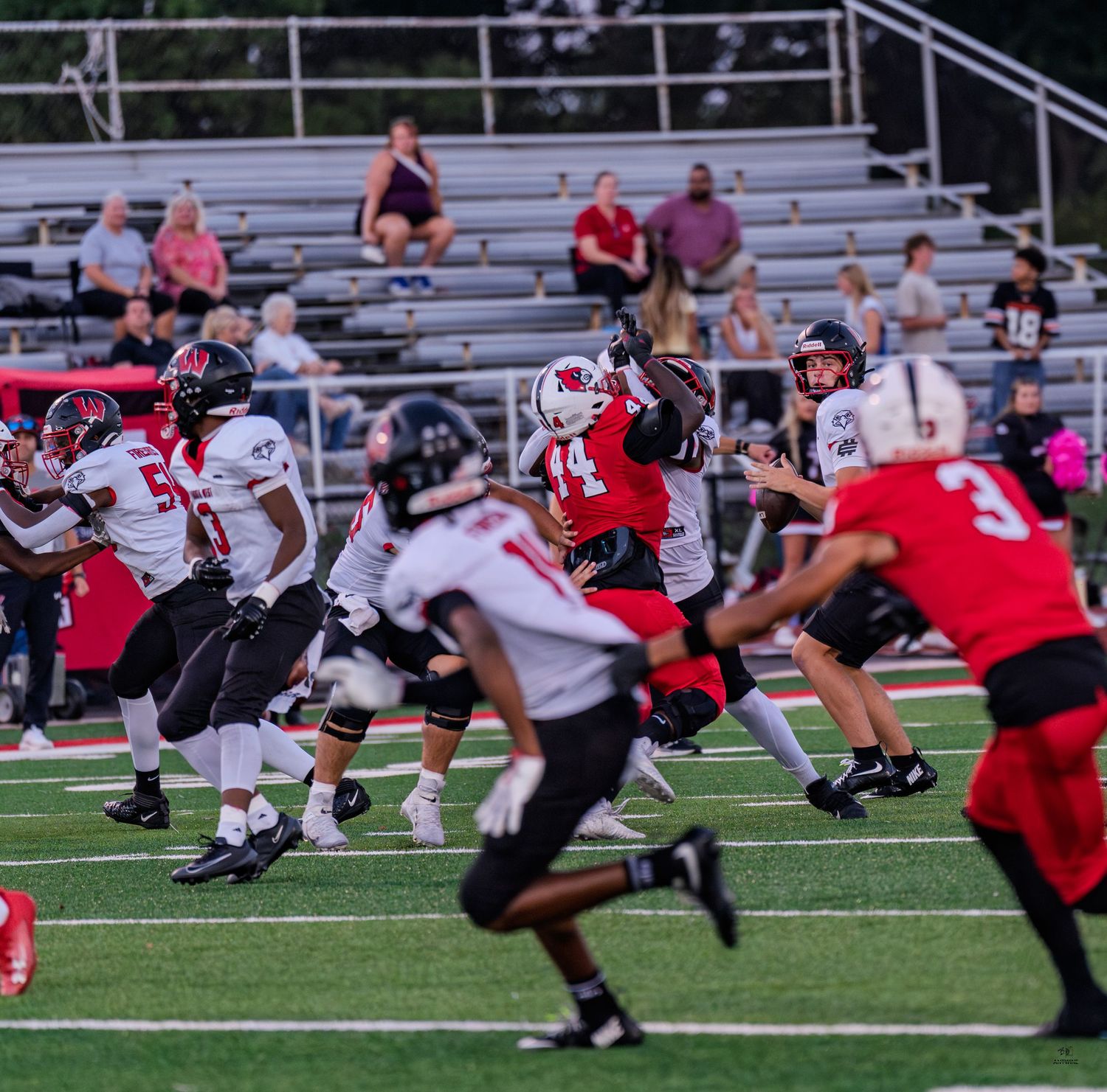 Colerain number 14 leaps to catch a pass during a high school football game under stadium lights.