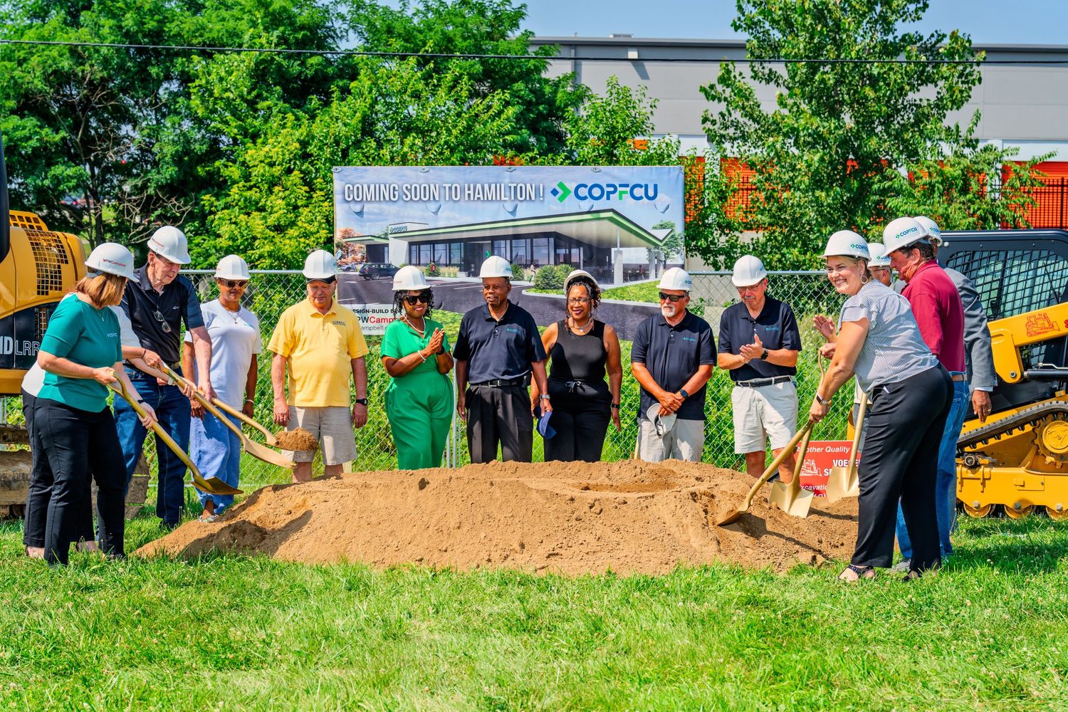 Team of officials in white hard hats breaking ground at new COPFCU branch location in Hamilton.