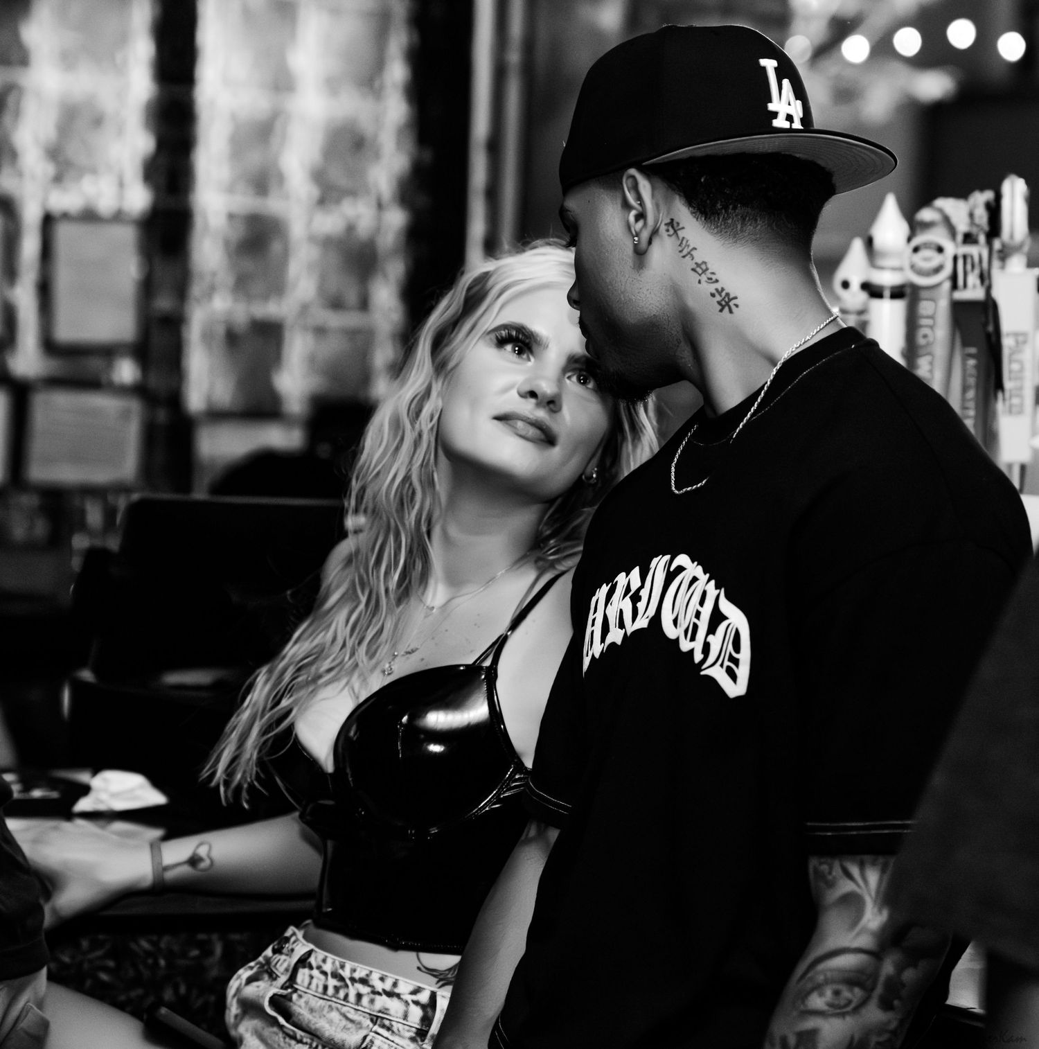 A couple shares an intimate moment in a black and white photo inside a bar.