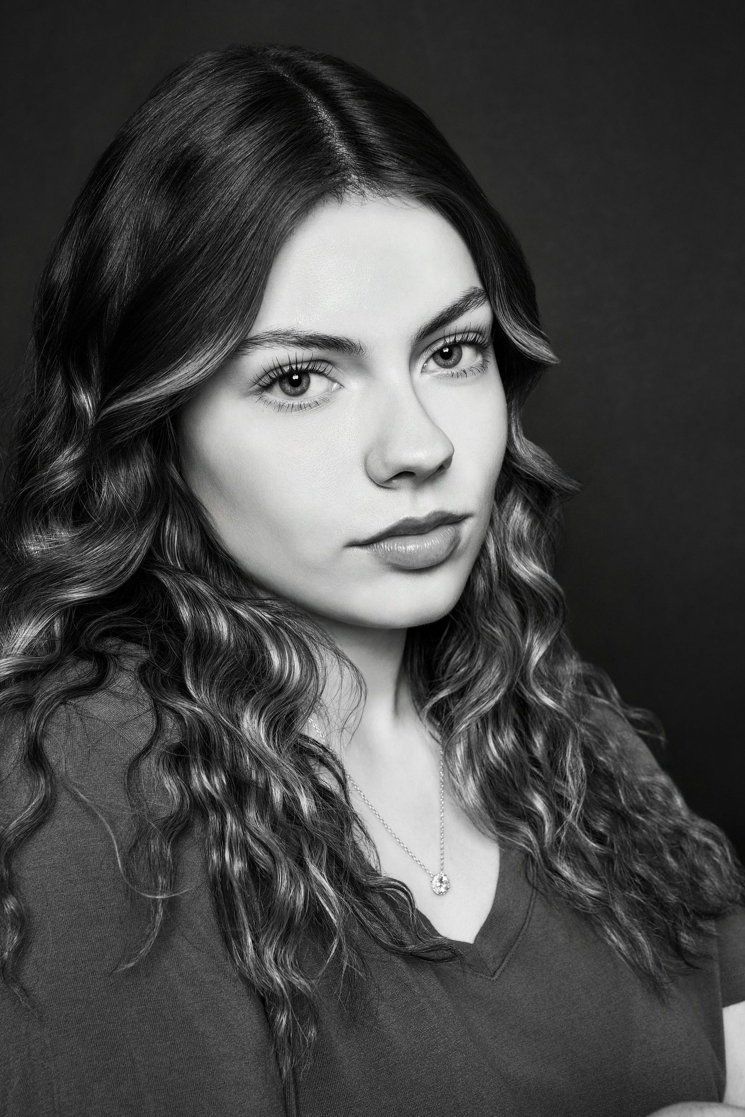 Black and white portrait of a young woman with wavy curly hair gazing confidently at the camera.