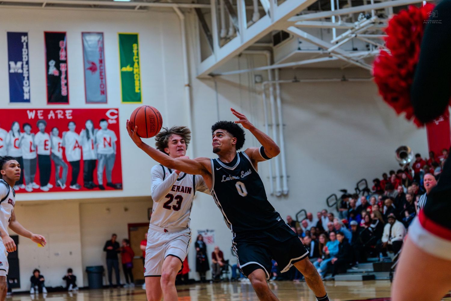 Basketball player number 23 attempts a layup while defended during a high school basketball game.