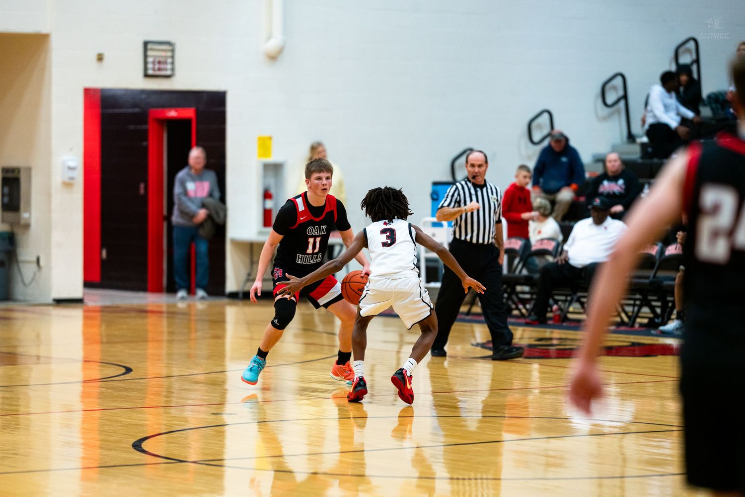 A basketball player wearing number 3 dribbles past a defender during a high school basketball game.