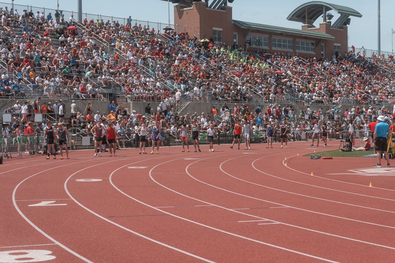 Track and field athletes compete in a distance running event before a large crowd at Ohio State University.