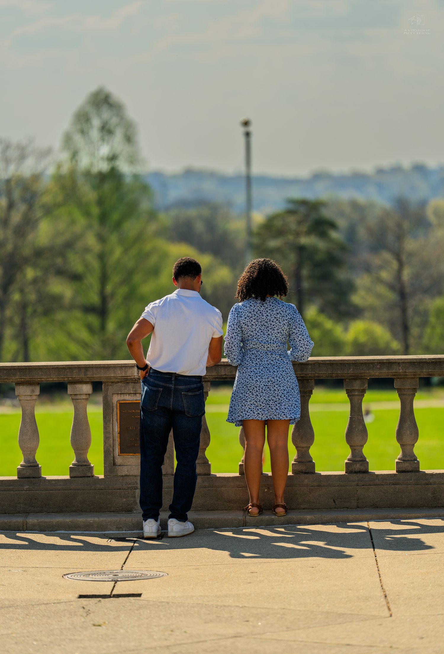 Couple enjoying scenic green park view from elegant stone balcony terrace together.