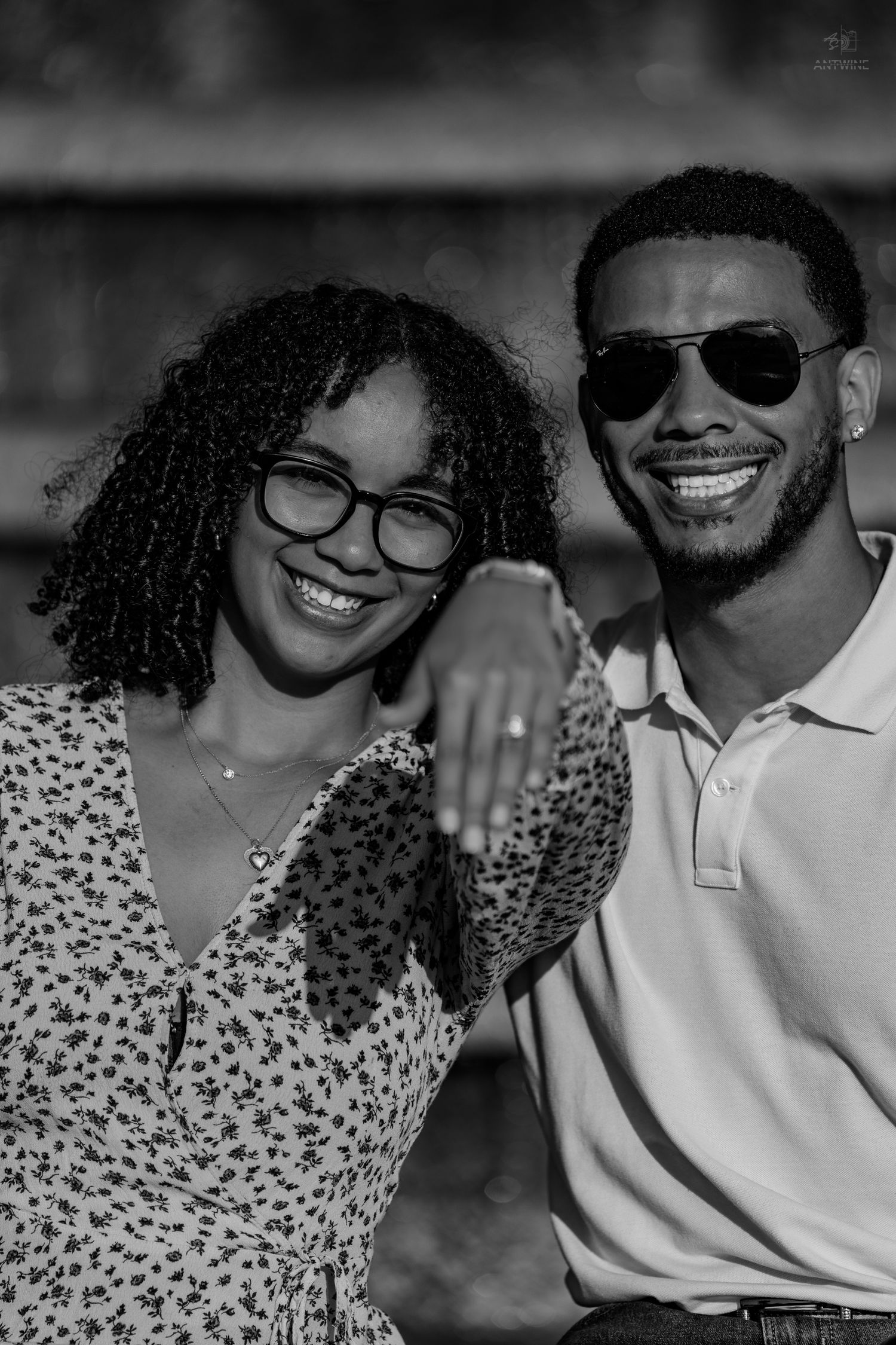 A joyful Black couple smiles closely together, the woman wearing glasses and the man in sunglasses.