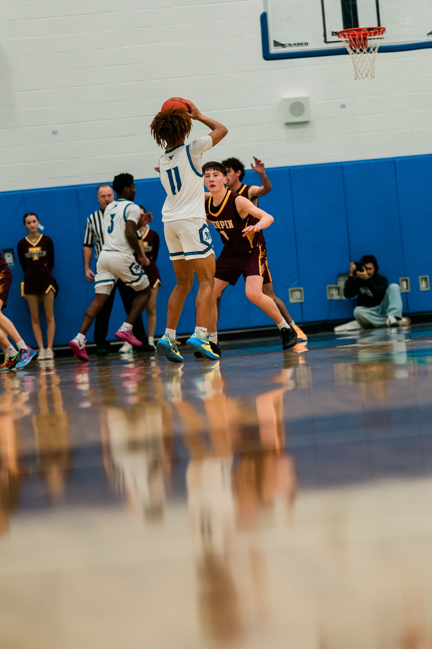 Warriors player #11 holds ball overhead while Turpin defender attempts to block during high school basketball.