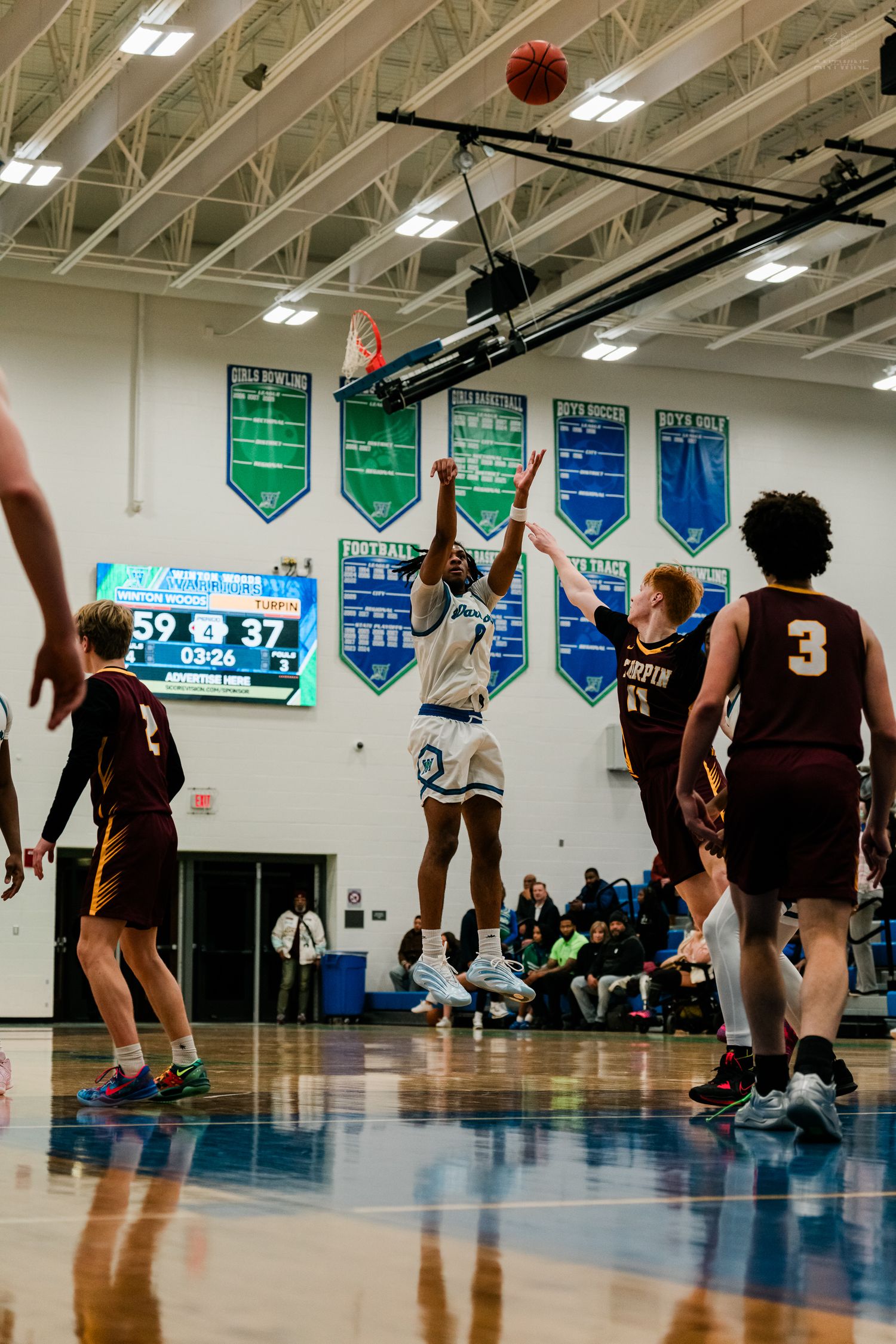 A Winton Woods player shoots a jump shot with the scoreboard showing 59-37 during a high school basketball game.