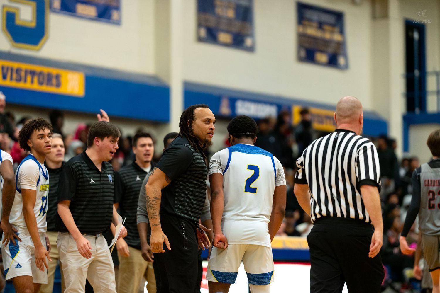 A basketball coach disputes a call with a referee during a high school basketball game.