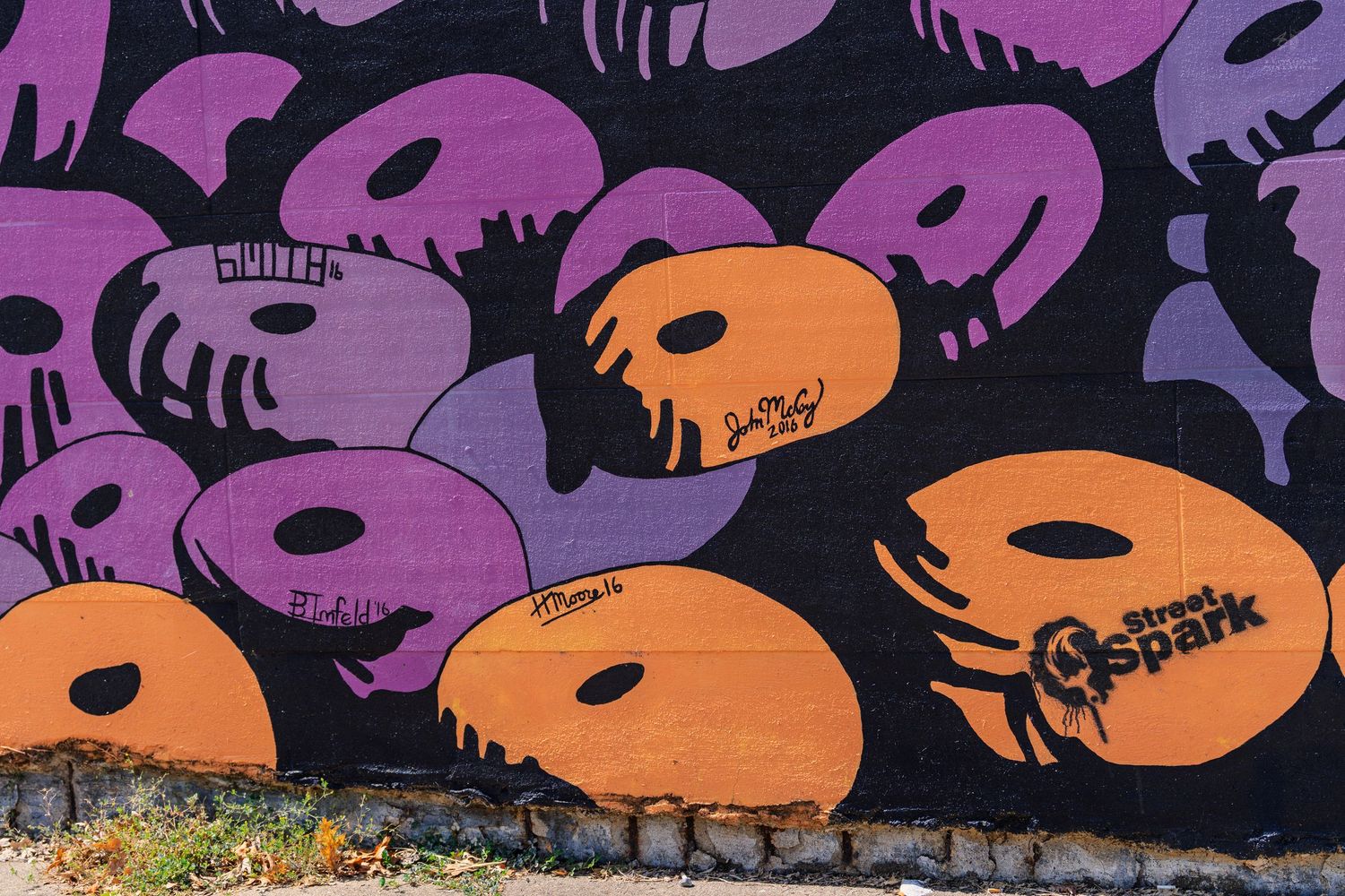 Colorful street art mural featuring purple and orange abstract shapes on a black wall with Street Spark graffiti logo.