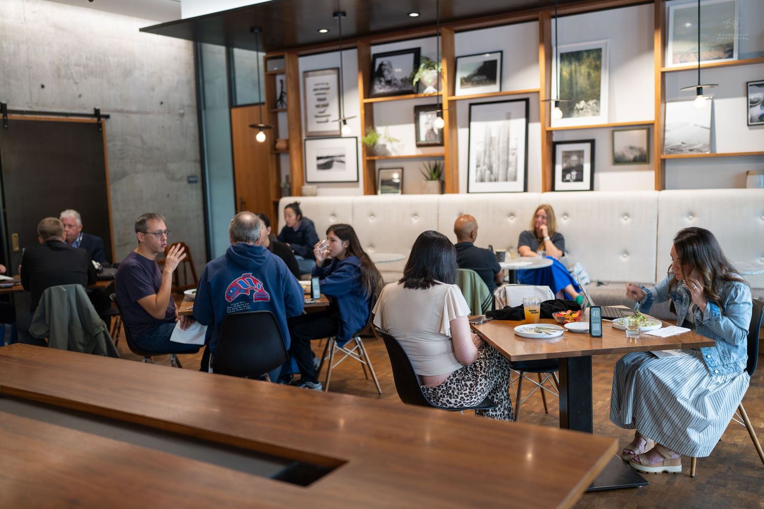 People seated at tables in a modern cafe during a group meeting or workshop.
