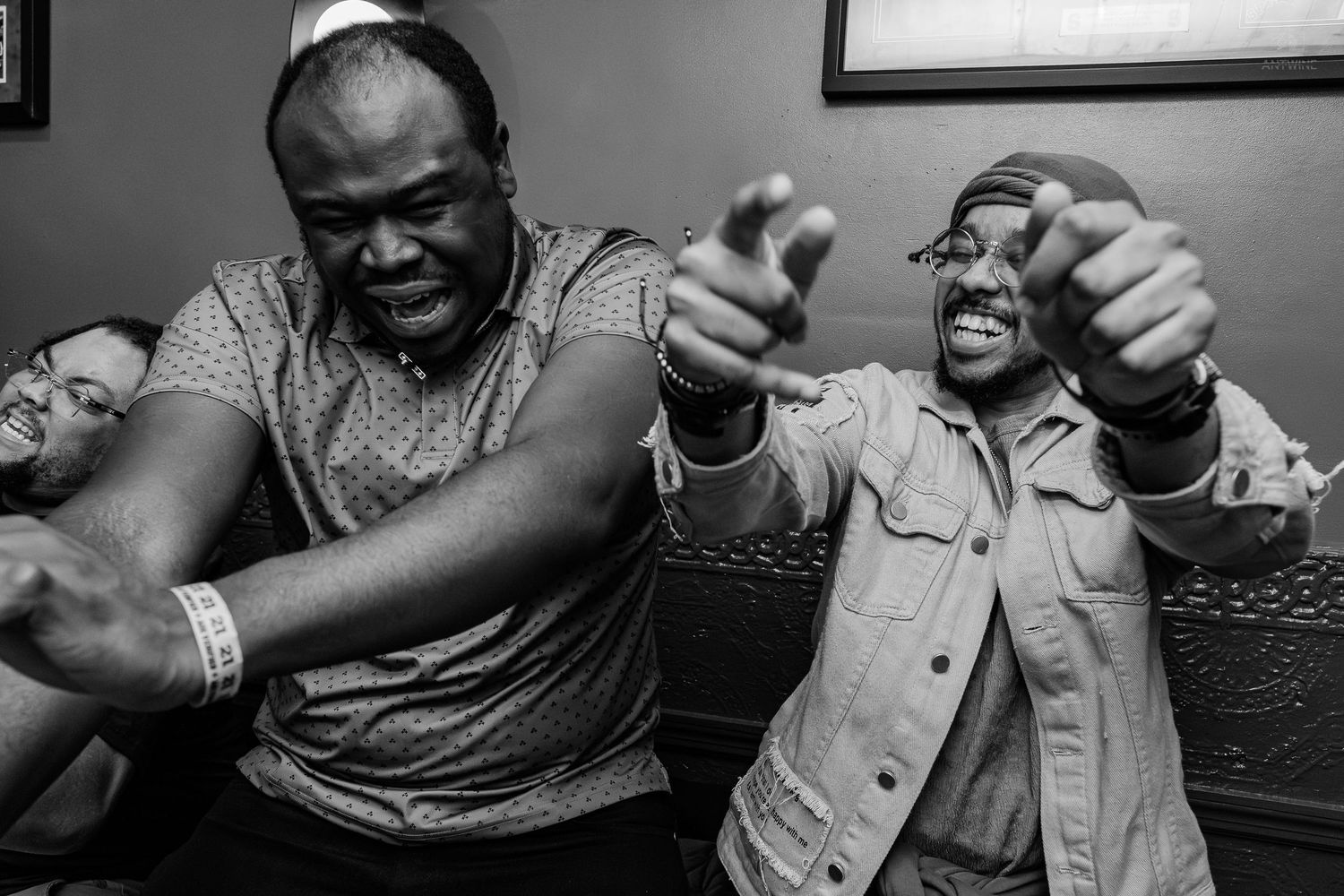Two men laughing and pointing at camera in lively black and white candid photo.
