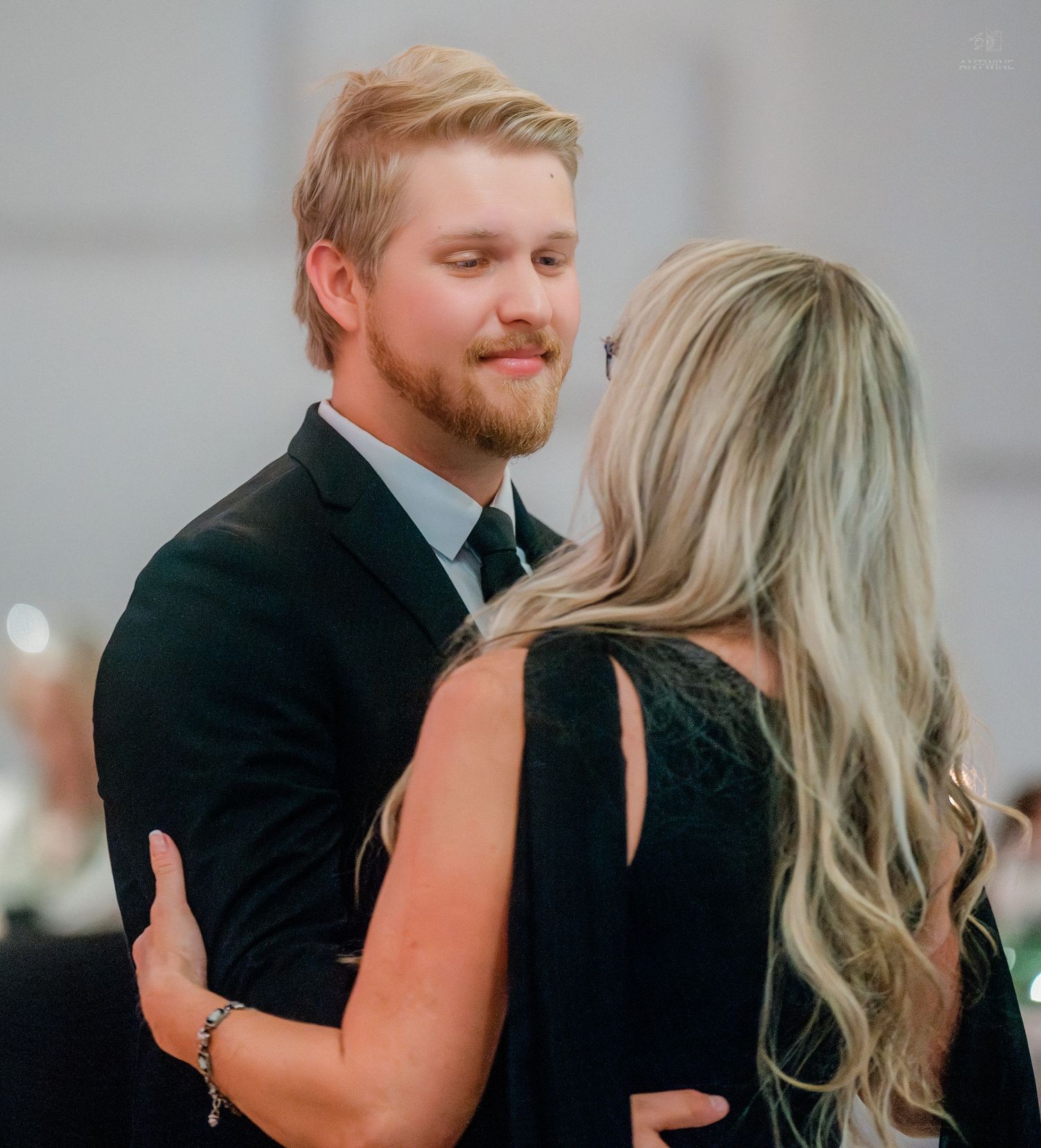 Young couple shares intimate dance moment at wedding reception in black and white portrait.