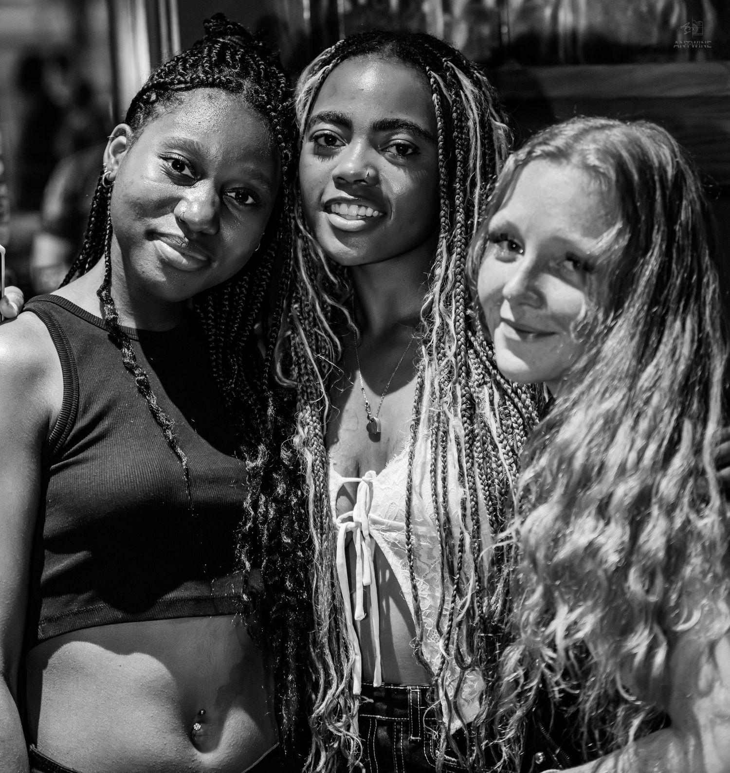 Black and white photo of three young women smiling together outdoors.