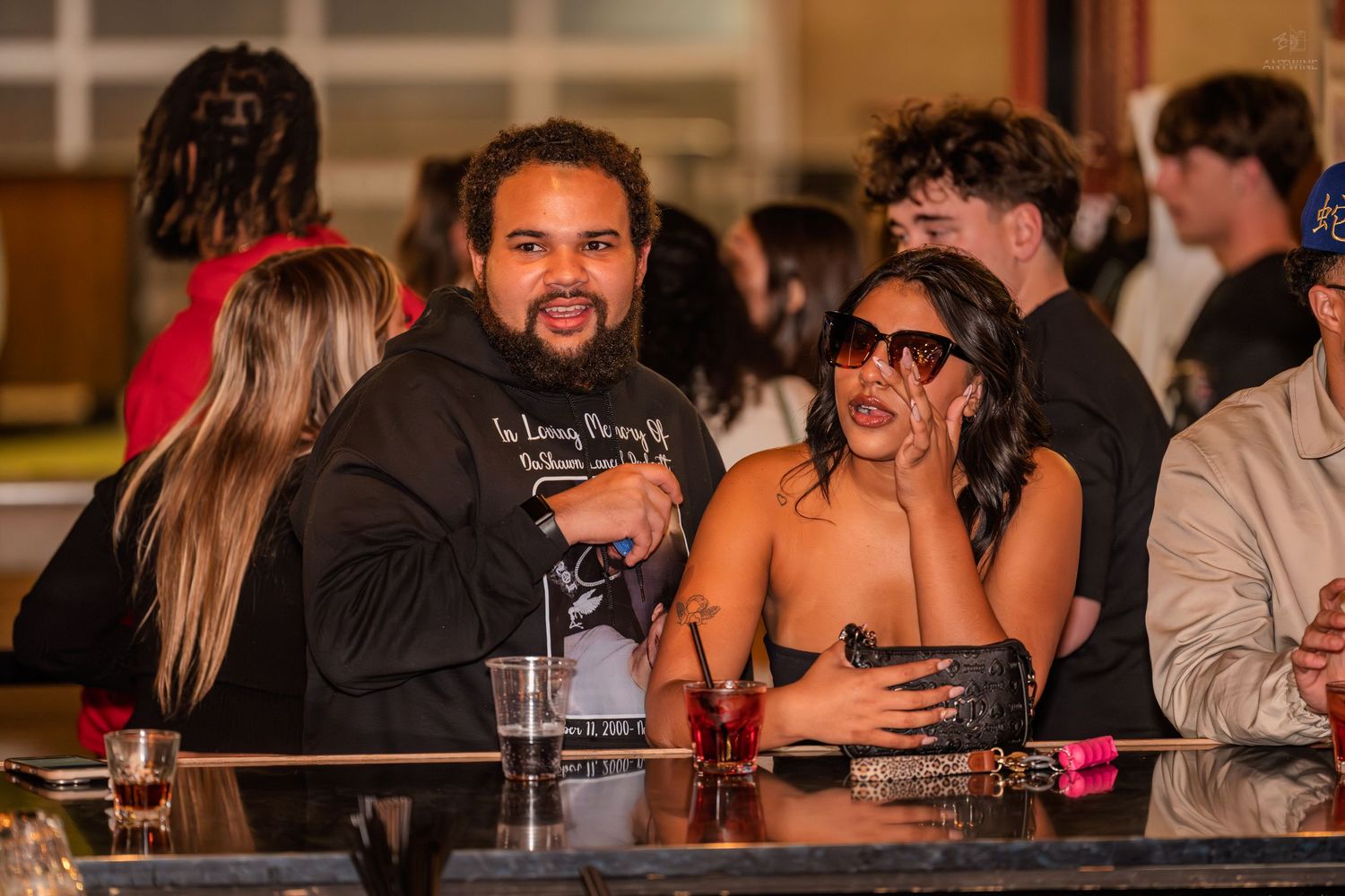Man and woman posing together at a bar during a nightclub event.