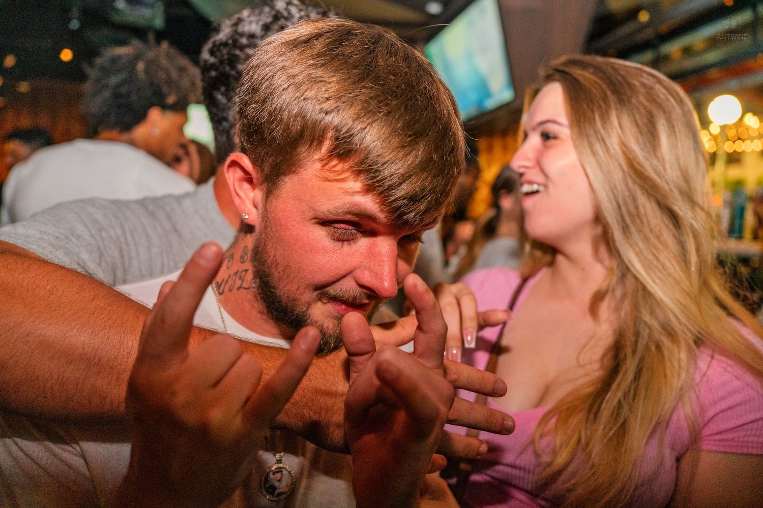 Man and woman at a bar examining something in their hands while laughing together.