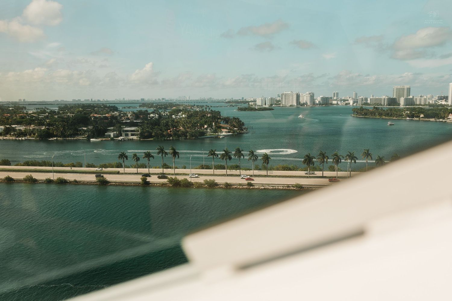 Aerial view of Miami waterway with palm tree islands, city skyline, and blue waters on a sunny day.