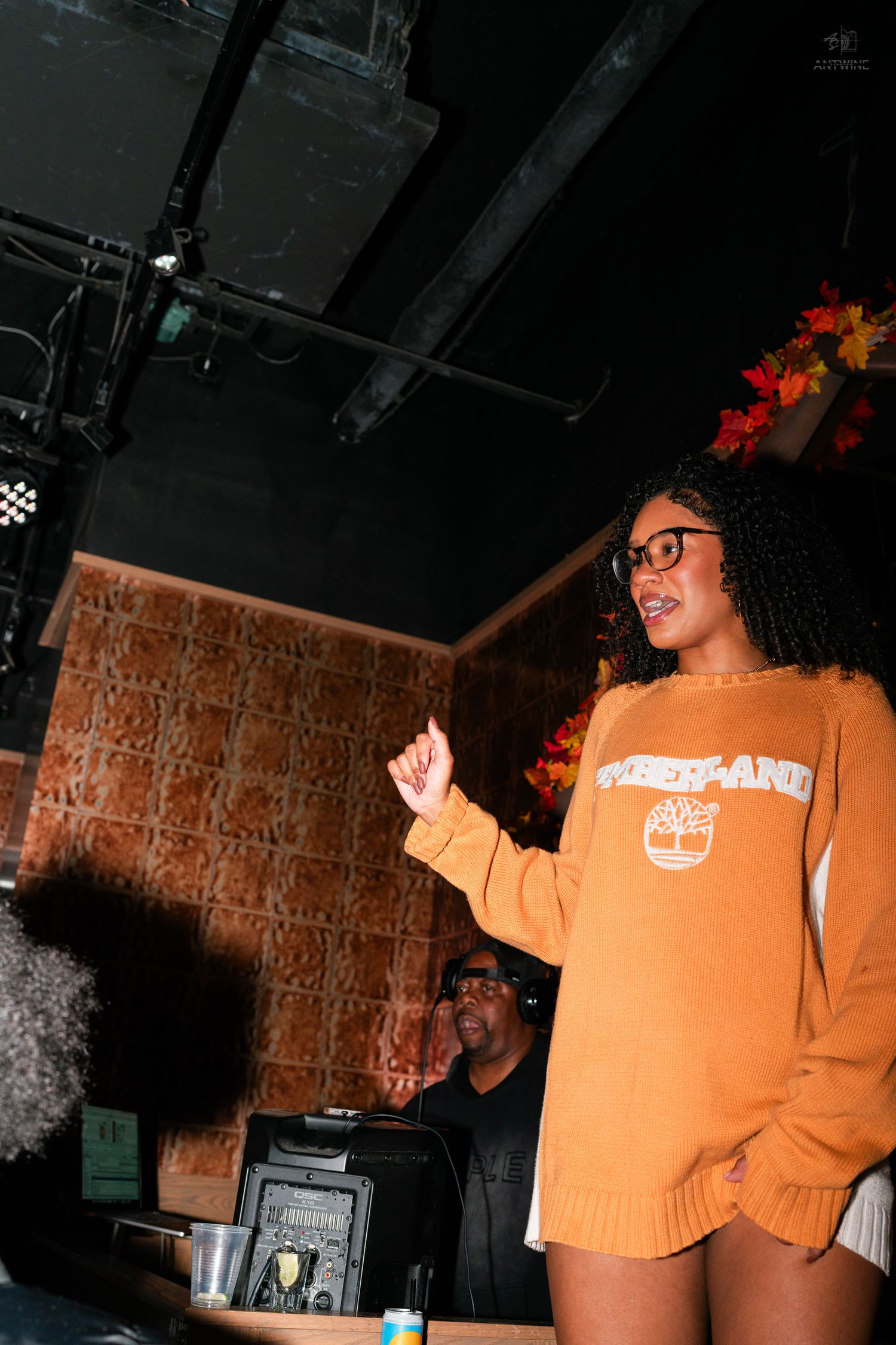 Young woman in orange Timberland sweater pointing at a Halloween party event in Cincinnati.