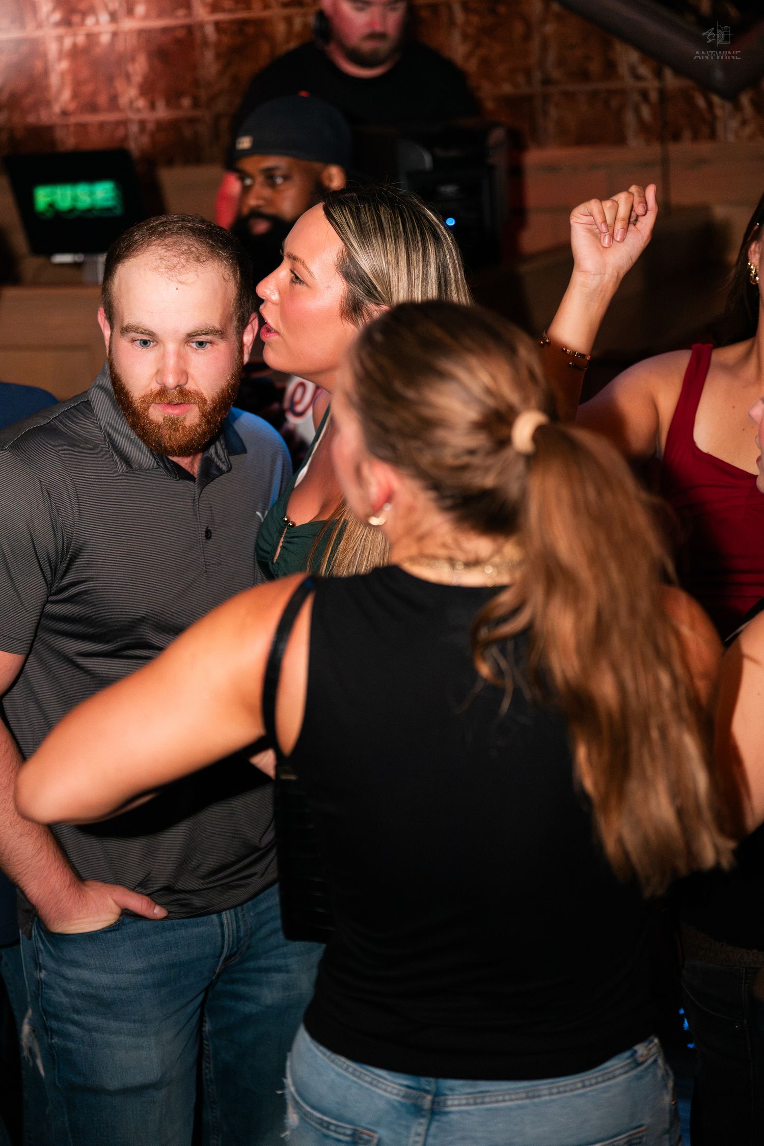 Group of people socializing at a nightclub with a FUSE sign visible in the background.