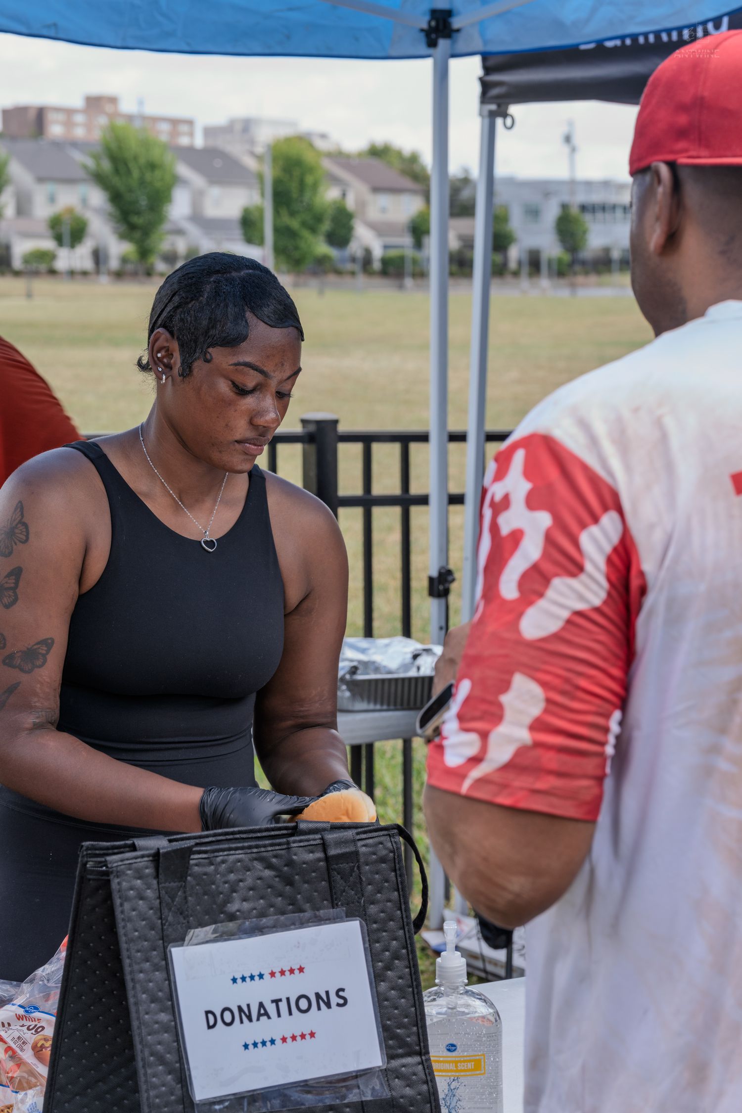 Volunteer collects donations at a charity event outdoors with a donations box.