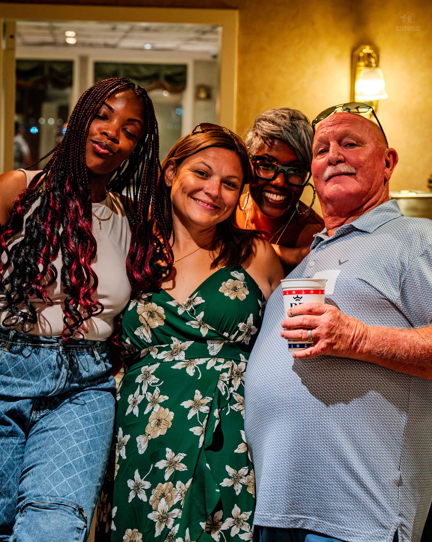 Four people posing and smiling together at a warm indoor social gathering event.