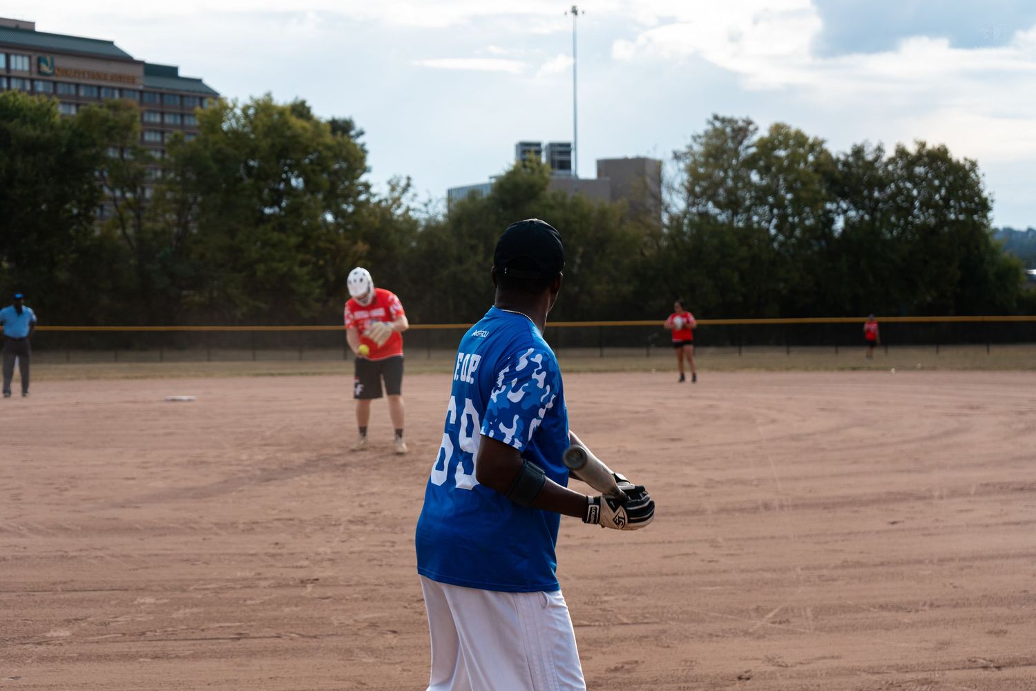 A softball player in a blue number 99 jersey prepares to throw the ball on a dirt field.