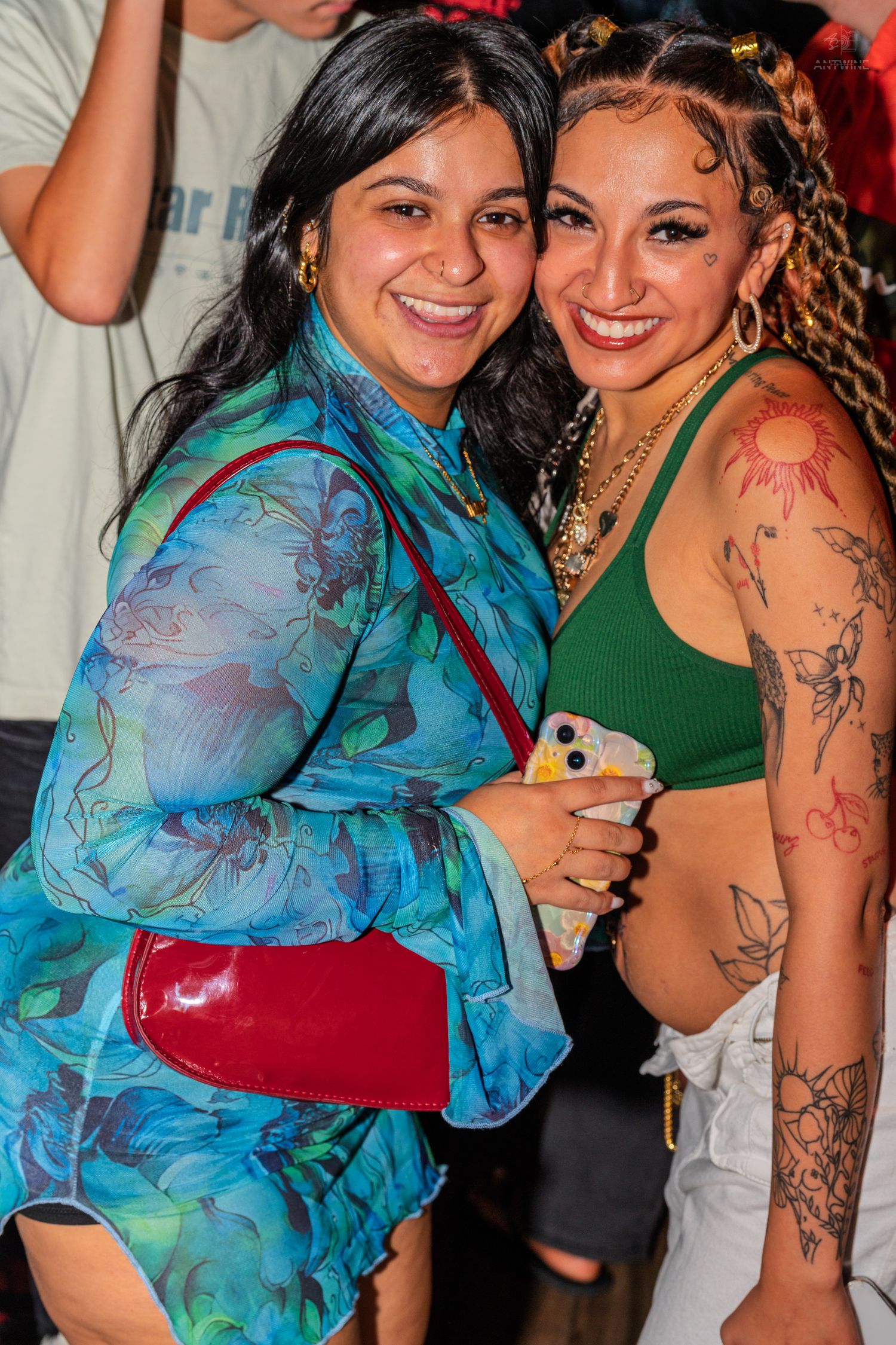 Two women smiling and posing together at a party, one in a floral blue top.