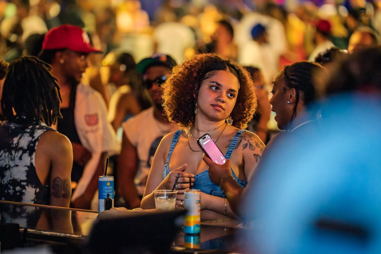 Young woman holds phone at a crowded outdoor nighttime concert event.